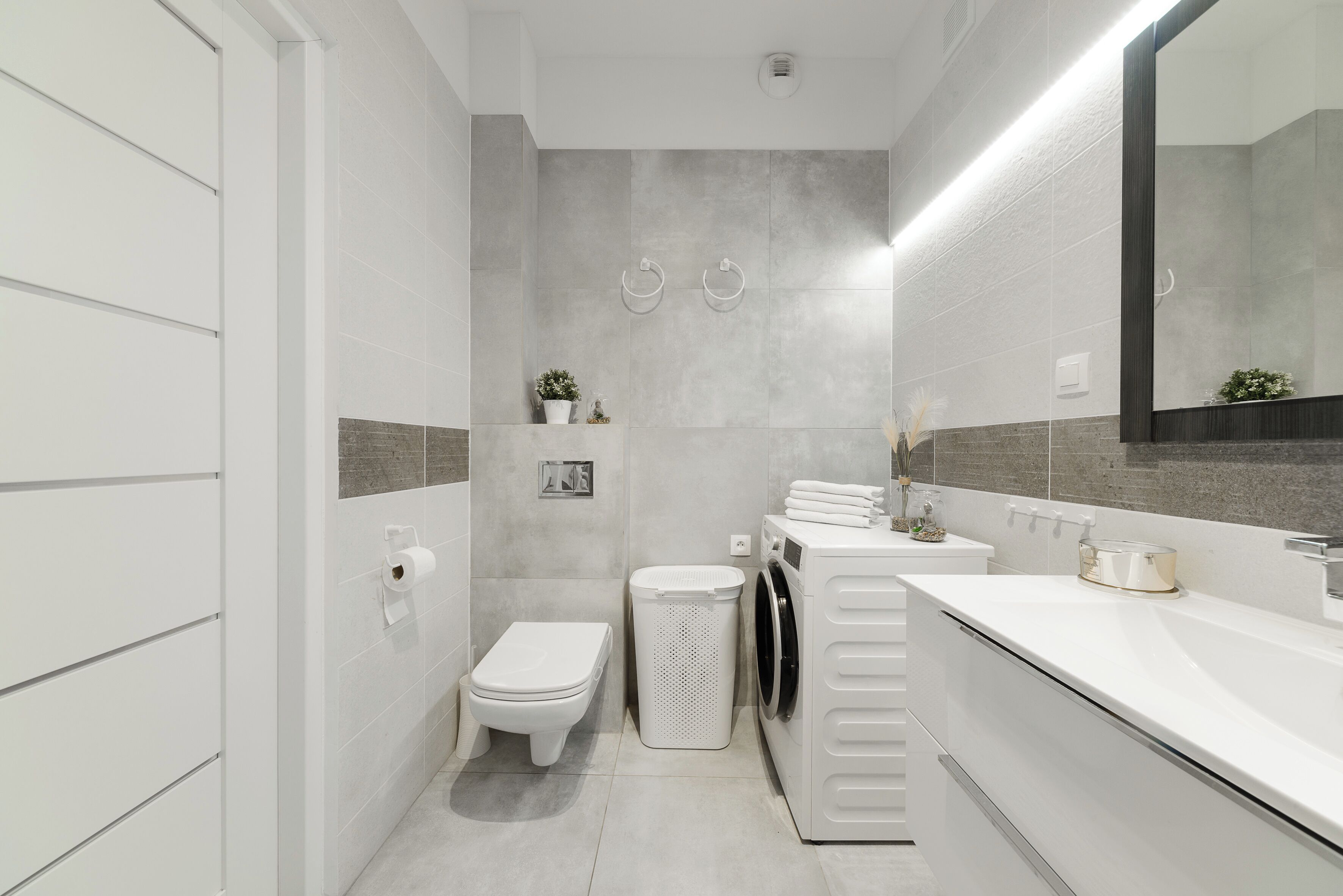 Ein modernes Badezimmer mit Toilette, Waschbecken und Waschmaschine.