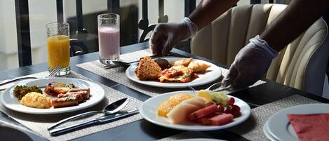 Une table à manger avec différents plats, notamment des pâtes, une salade et un verre de jus d’orange.