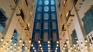 A hotel interior with a central atrium, multiple floors, and string lights. - Central Inn Souq Waqif (Doha)