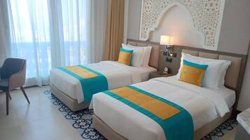A hotel room with two beds, a chair, and a decorative wall piece.