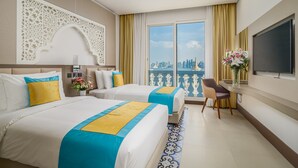 A hotel room with two beds, a desk, a TV, and a balcony with a city view. - Central Inn Souq Waqif (Doha)