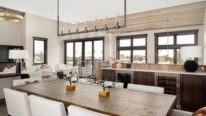 A modern kitchen with a large island, white chairs, and a dining table. - Ski-In/Ski-Out | Hot Tub | Game Room (Big Sky)