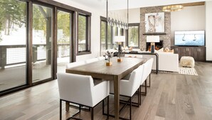 A modern living room with a large dining table, white sofas, and a fireplace. - Ski-In/Ski-Out | Hot Tub | Game Room (Big Sky)