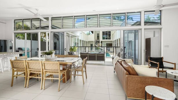 A spacious open-plan living area with a dining table, chairs, and a sofa.