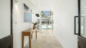 A hallway with a wooden console table, a painting, and a staircase leading to a pool area.
