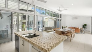 A modern kitchen with a large island, a dining area with a table and chairs, and a view of the outside.