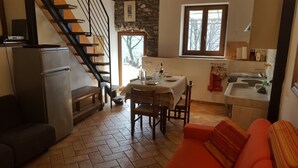 A compact living space with a dining area, a kitchen, and a staircase. - La Campanelle (Montemezzo)