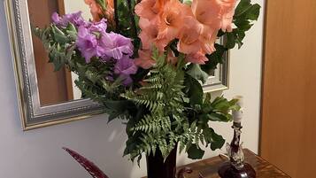 A floral arrangement in a vase on a wooden table with a mirror and framed picture in the background.
