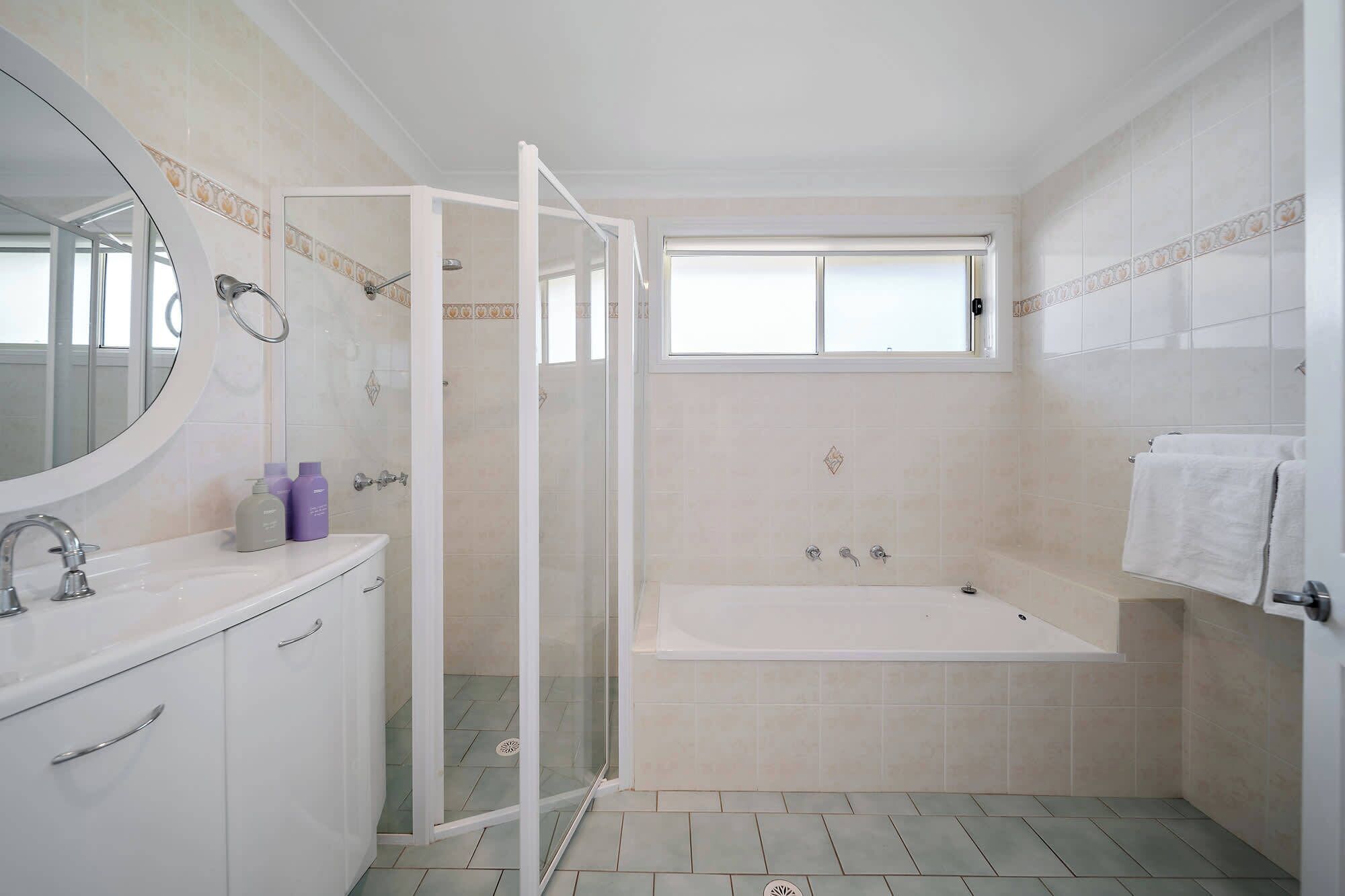 A bathroom with a shower, a bathtub, a sink, and a window.