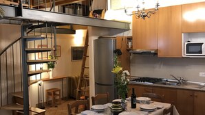 Eine Küche mit Holzausstattung, einem Edelstahlkühlschrank, einem Gasherd und einem Essbereich mit Tisch für vier Personen.