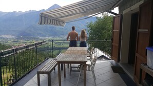 Ein Balkon mit Tisch und Stühlen mit Blick auf eine gebirgige Landschaft.