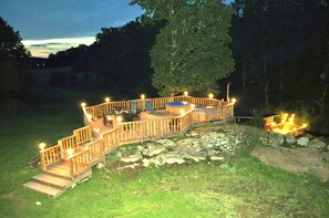 Eine Holzterrasse mit Geländer, einem Whirlpool und einem kleinen Tisch mit Stühlen.