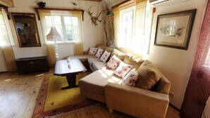A cozy living room with a sofa, a coffee table, and a rug. There is a mirror, a lamp, and a framed picture on the wall.