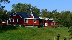 A red barn with a white roof and a white fence.