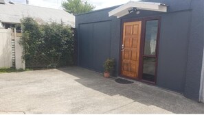 Enter a residence with a single-story building featuring a wooden door and a concrete driveway.