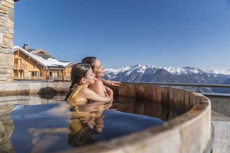 A couple in a hot tub with a mountain backdrop.