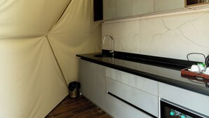 Uma cozinha compacta com bancada preta, forno embutido e pia.