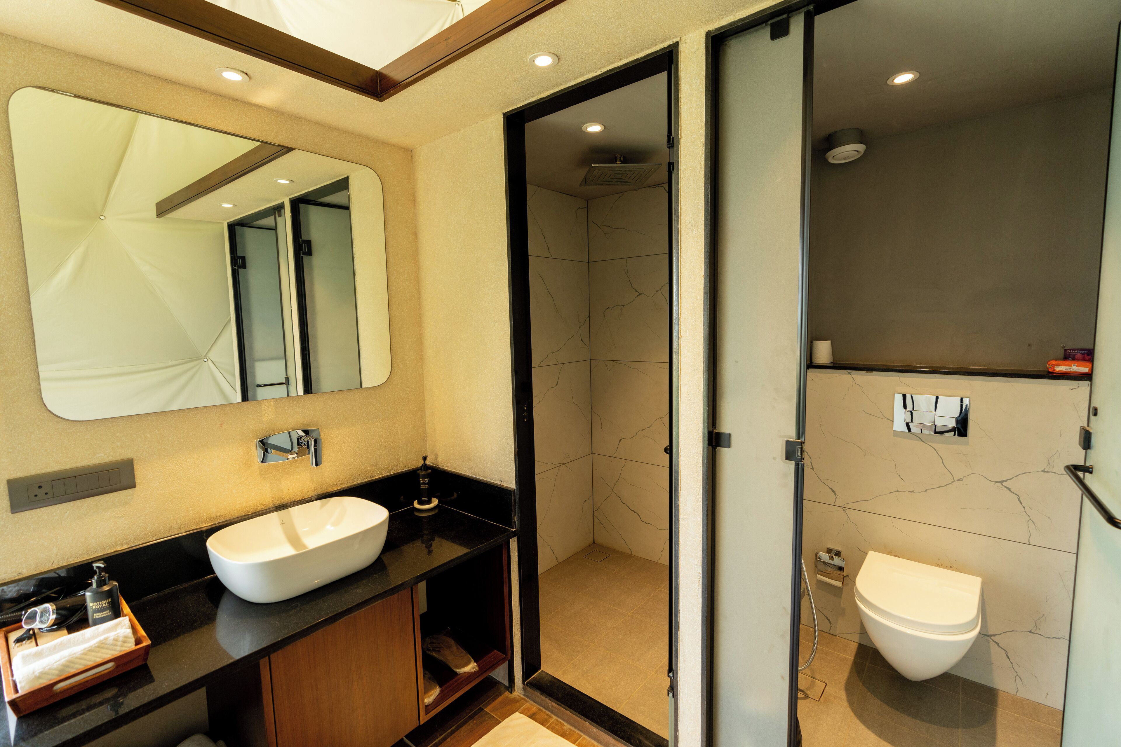 Un baño moderno con un espejo grande, un lavabo blanco y un inodoro separado.