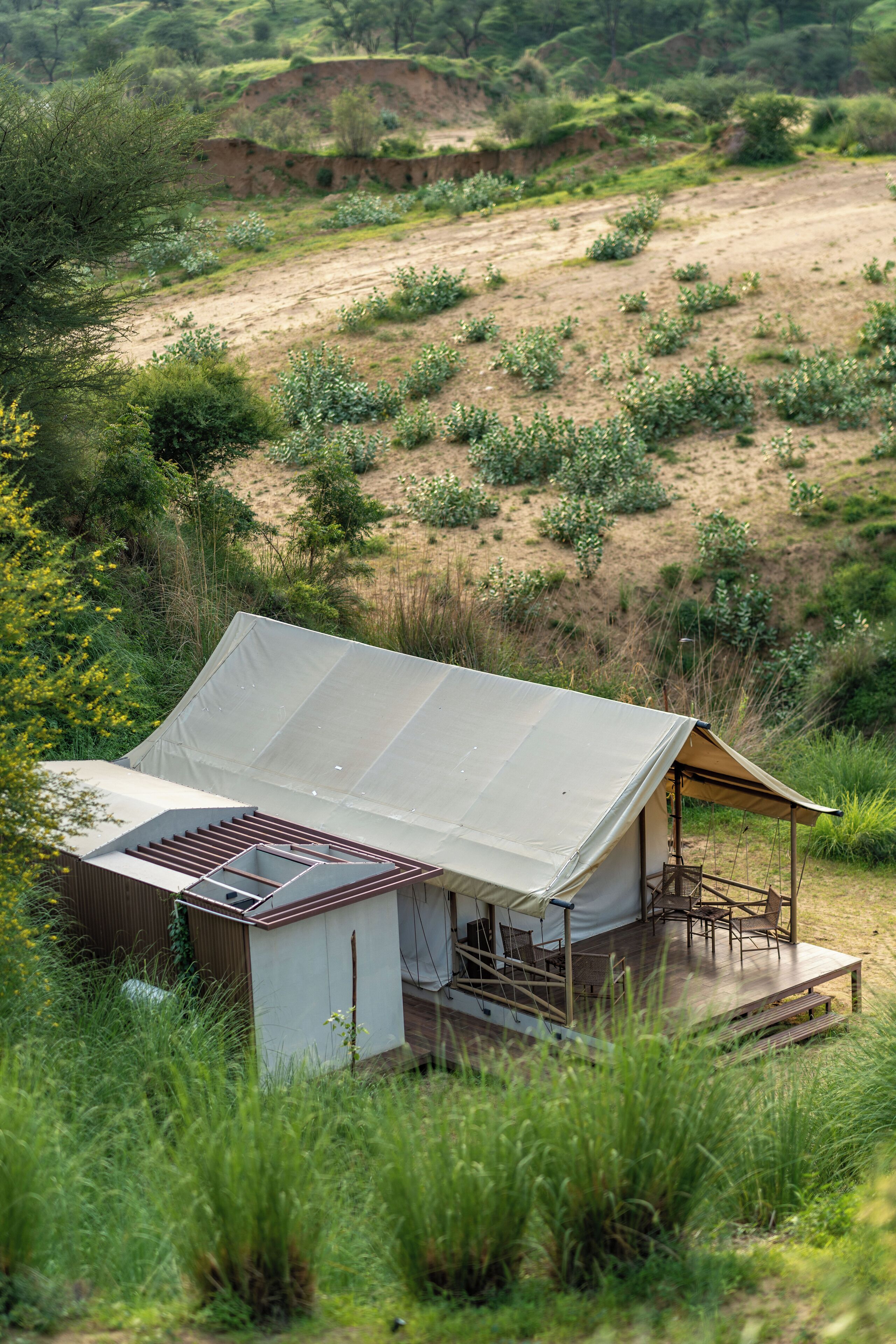 Eine Zelthütte mit flachem Dach, einer Holzterrasse und einem Sitzbereich.