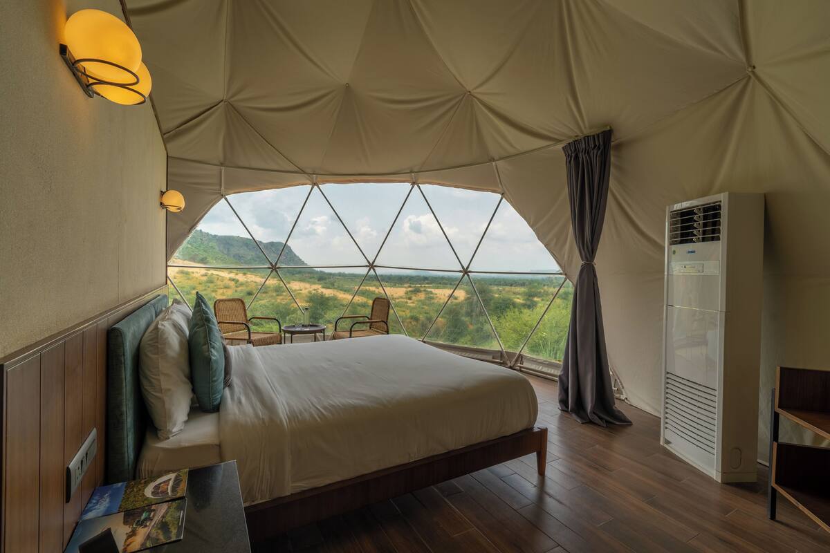 A tented room with a bed, a table, and chairs.