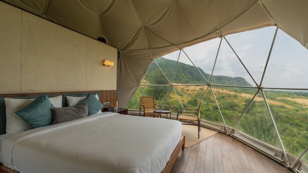Um quarto com tenda, uma cama, uma cadeira e uma mesa.