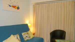 Ein Wohnzimmer mit einem blauen Sofa, einem schwarzen Sessel, einem kleinen Tisch und einem Gemälde an der Wand.