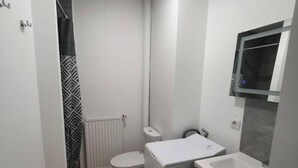 Un baño pequeño con inodoro, lavamanos y zona de ducha.