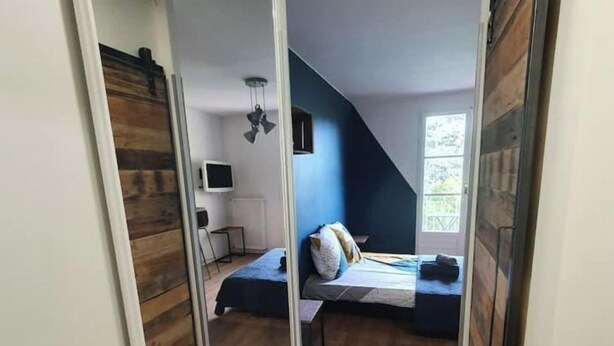 Un dormitorio con techo inclinado, cama, escritorio y ventana.