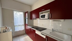 Una cocina moderna con armarios rojos, una encimera blanca y un microondas integrado.