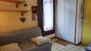 A cozy living room with a sofa, a wardrobe, and a door with a curtain. - Cozy Studio for 4 in Village Center, Near Slopes and Shops (Les Carroz d'Arâches)