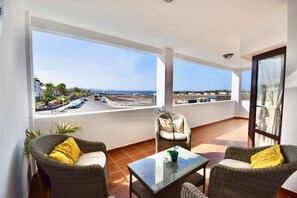 A balcony with wicker furniture, a glass table, and a view of the sea and parking lot. - Villa Private Heated Pool And Sea Views WIFI and English Satellite TV (Playa Blanca)