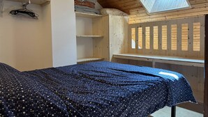 A bedroom with a bed, a skylight, wooden shelves, and a window with shutters. - Cozy Mezzanine Studio in Village Center with Balcony (Villard-de-Lans)
