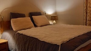 Ein Schlafzimmer mit einem Bett, zwei Nachttischen, einer Lampe und einem Vorhang.