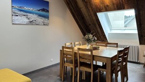 Ein Essbereich mit Holztisch und Stühlen, einer Blumenvase, einem Landschaftsbild und einem Oberlicht.