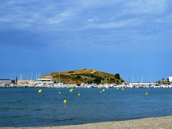 Enjoy waterfront views of a marina with boats docked and a pebbly beach.