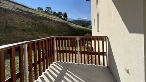 A balcony with a view of a grassy hill and mountains in the distance. - Cozy Apartment with Balcony, WiFi, and Free Parking near Ski Slopes (Villard-de-Lans)