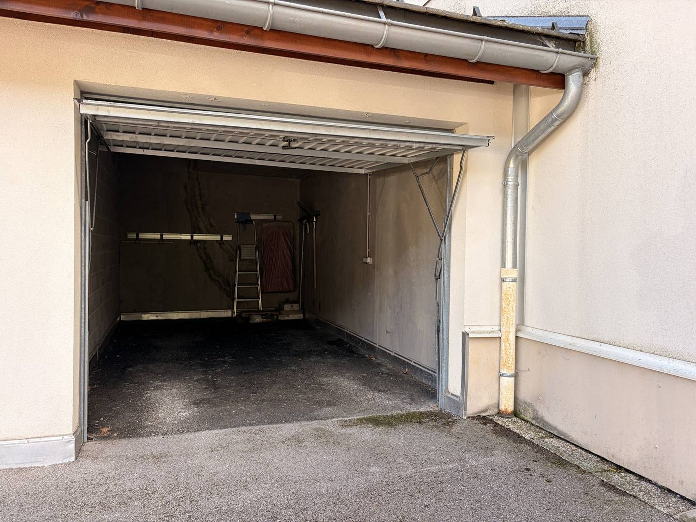 Un garage avec une porte en métal, une échelle et un poteau électrique.