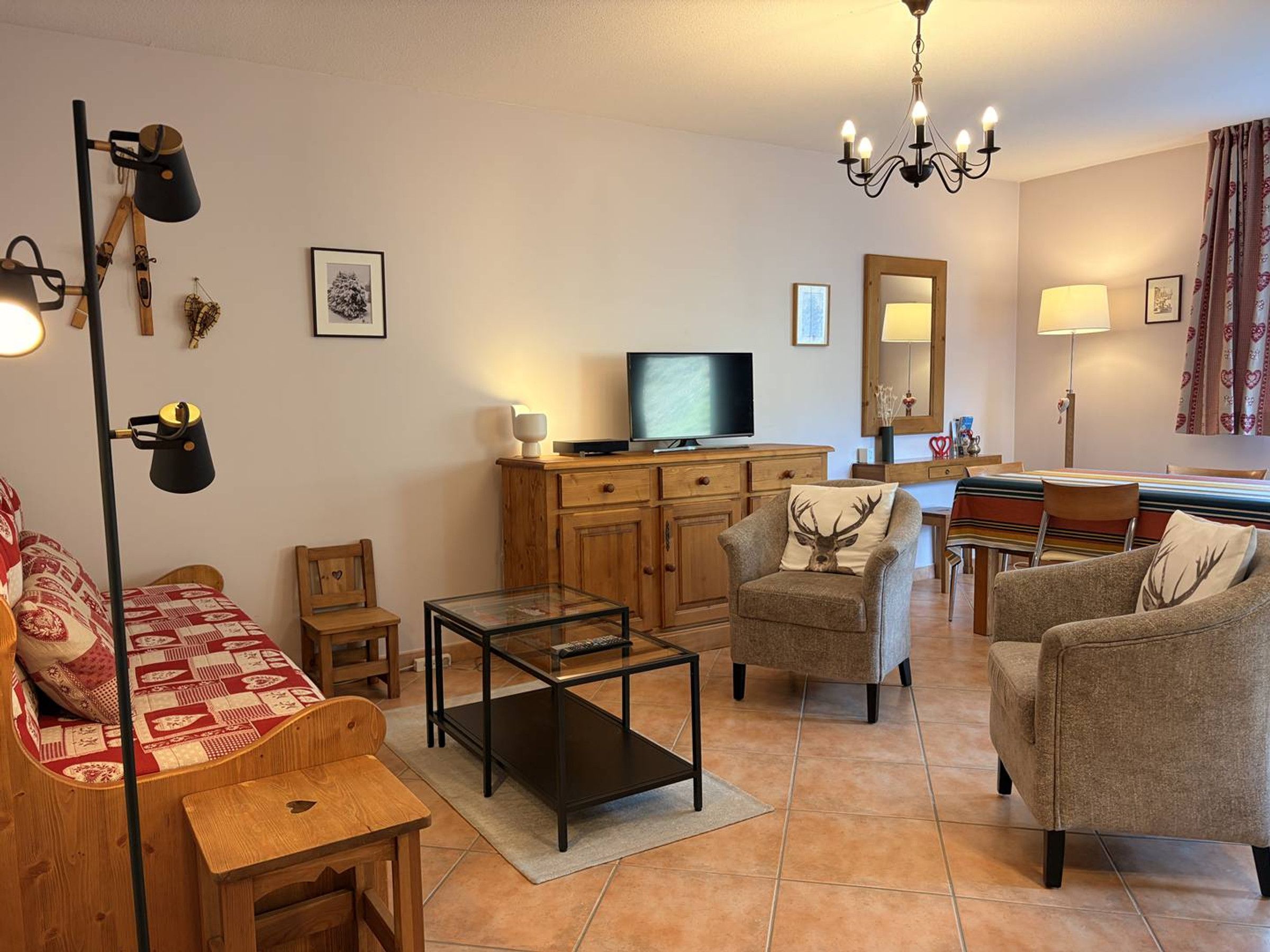 Sala de estar com televisão, mesa de centro e duas poltronas.
