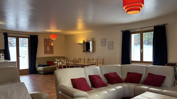 A spacious living room with a large white leather sofa, a wooden coffee table, and a dining area with a wooden table and chairs. - Spacious and functional house - 5 bedrooms, terrace, private parking (Villard-de-Lans)