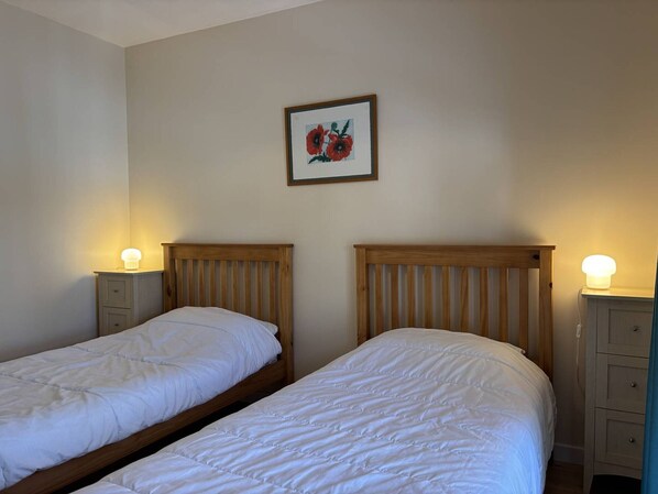 A room with two single beds, each with a wooden headboard and a bedside table with a lamp. - Spacious and functional house - 5 bedrooms, terrace, private parking (Villard-de-Lans)
