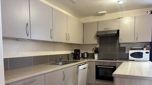 A modern kitchen with grey cabinets, a dishwasher, a stove, a microwave, and a coffee maker. - Spacious and functional house - 5 bedrooms, terrace, private parking (Villard-de-Lans)