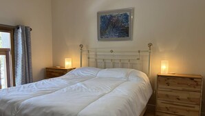 A bedroom with a bed, two bedside tables, a nightstand, a painting on the wall, and a window with curtains. - Spacious and functional house - 5 bedrooms, terrace, private parking (Villard-de-Lans)