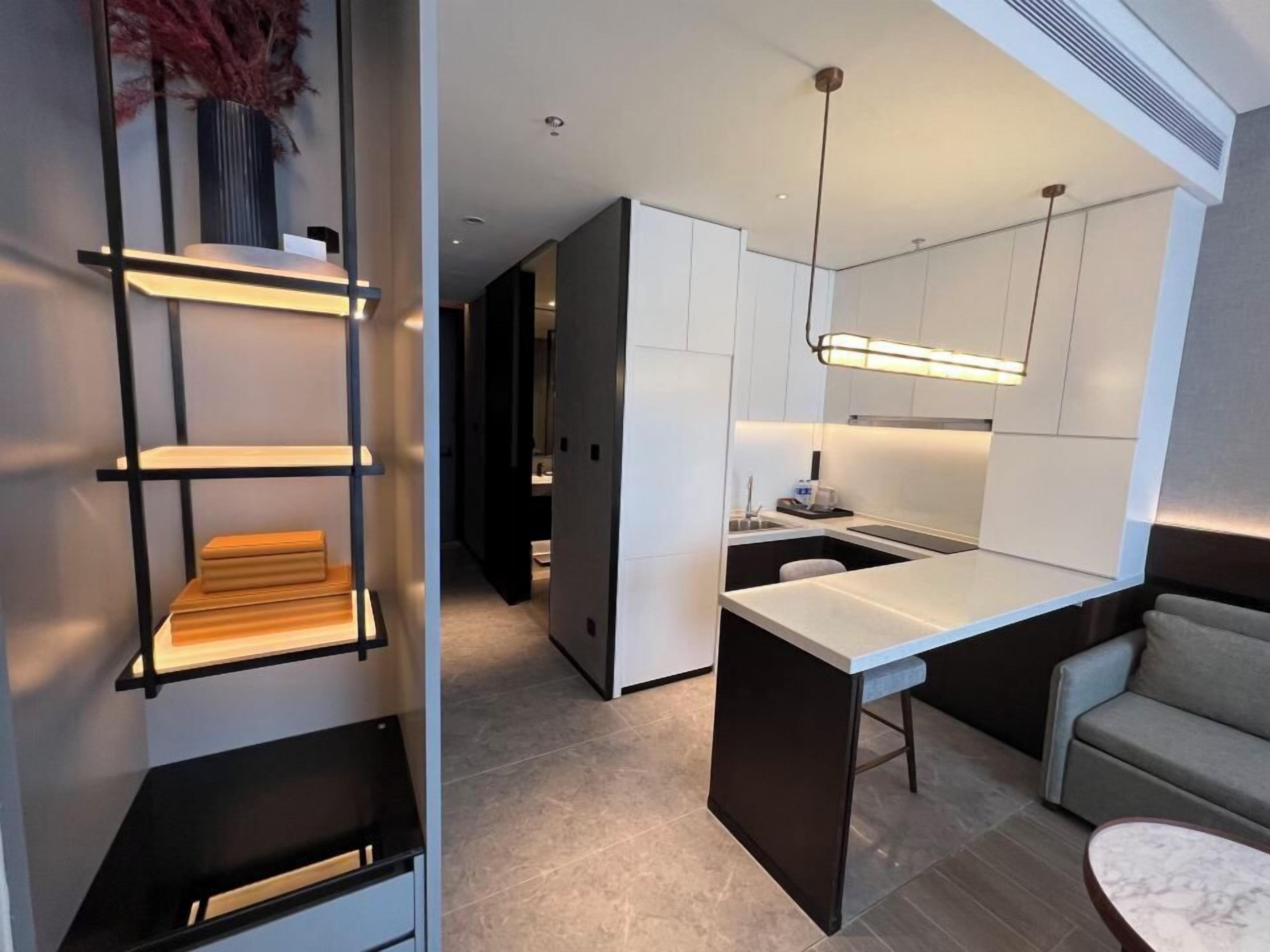 Une cuisine moderne avec des meubles blancs, un îlot central et un luminaire suspendu.