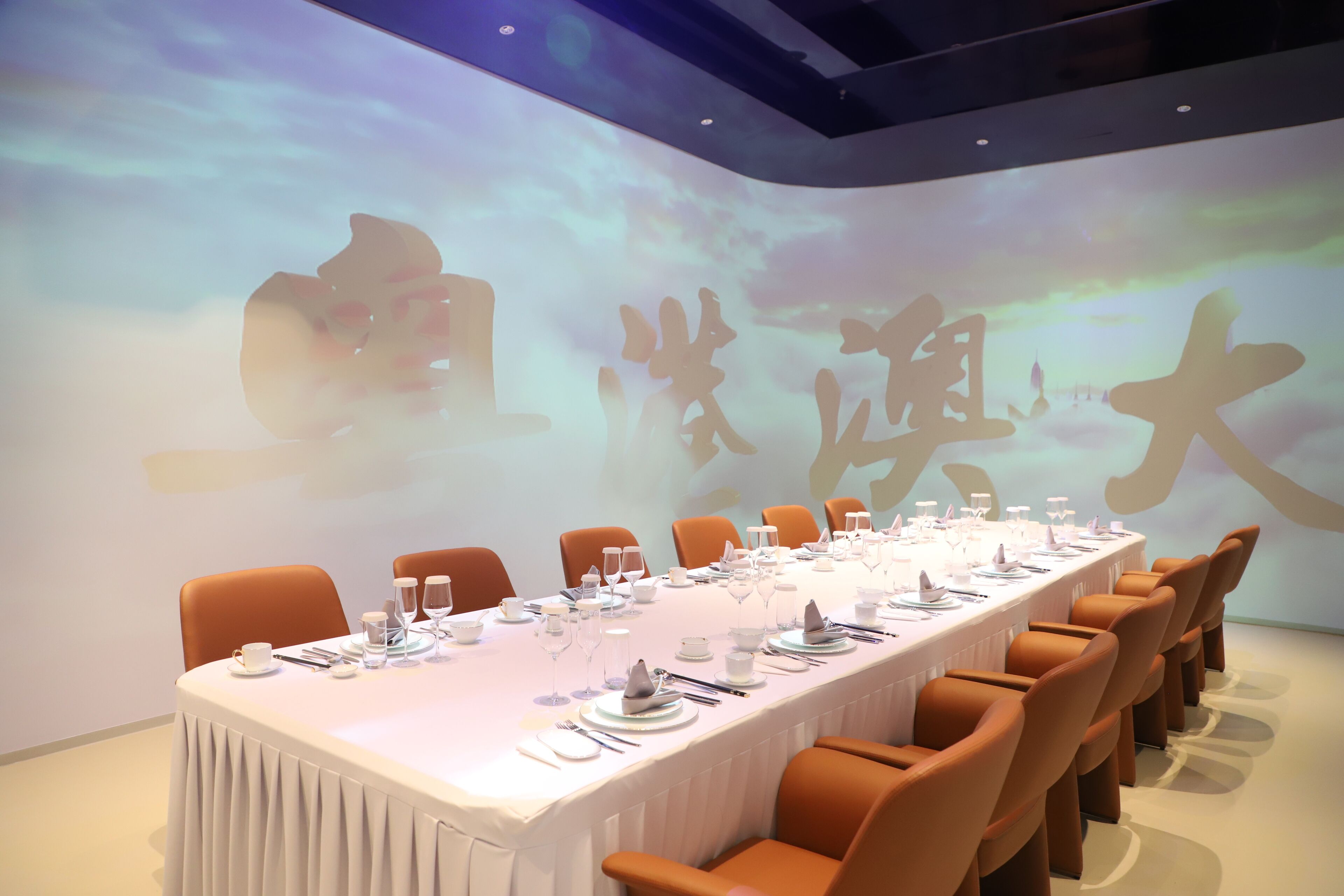 A conference room with a long table set for a meeting, surrounded by chairs.