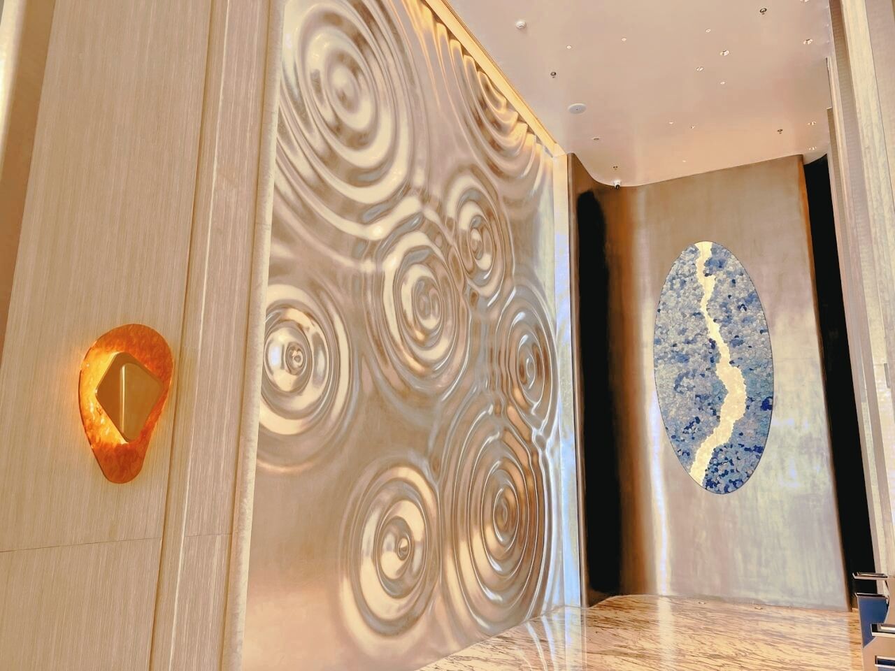 Ein modernes Interieur mit einer Marmorwand mit Wirbelmuster und einem großen, ovalen Kunstwerk.
