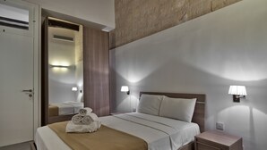Een hotelkamer met een bed, nachtlampjes, een nachtkastje, een spiegel en een deur.