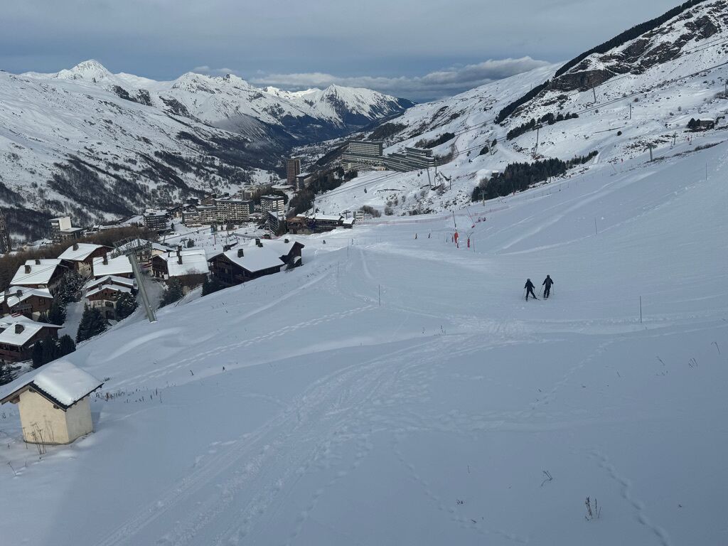 Eine verschneite Berglandschaft mit Gebäuden und einer Skipiste.