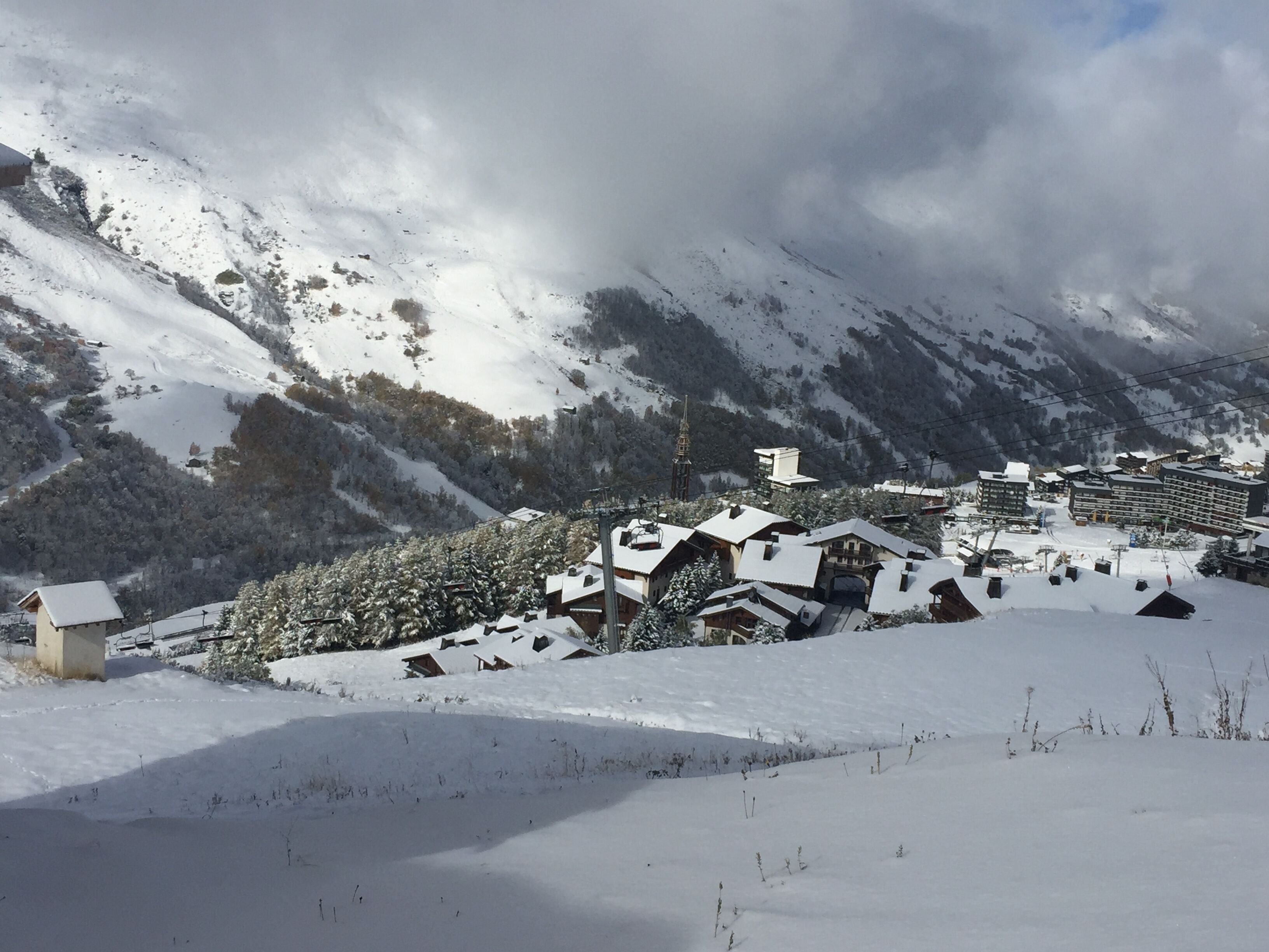 Un village enneigé, avec ses maisons traditionnelles en bois, une église et une chaîne de montagnes en arrière-plan.