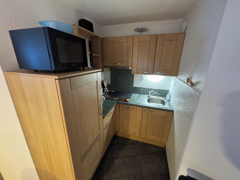 A compact kitchen with wooden cabinets, a microwave, and a sink.