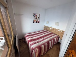 A bedroom with a bed, a wooden headboard, a radiator, and a painting on the wall. - At the foot of the ski slopes, sleeps 4–5. Elevation: 2,000 m. Exceptional view.   (Les Belleville)